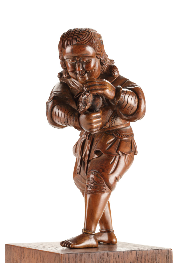 A fine boxwood Japanese okimono of a Dutchman playing with a bat