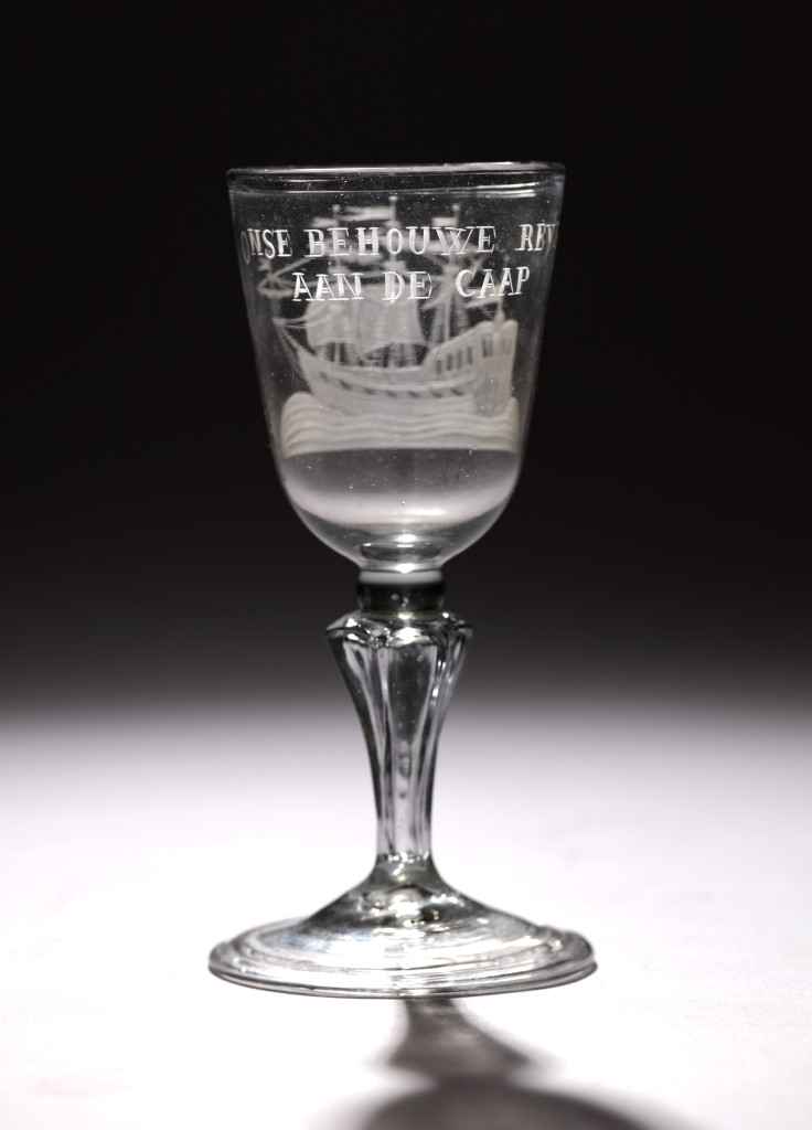 A glass with the engraving of an East-Indiaman with text