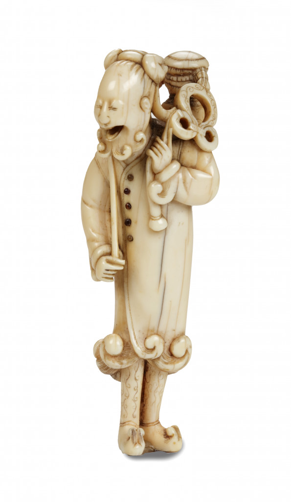 A tall ivory netsuke of a Dutchman holding a lantern