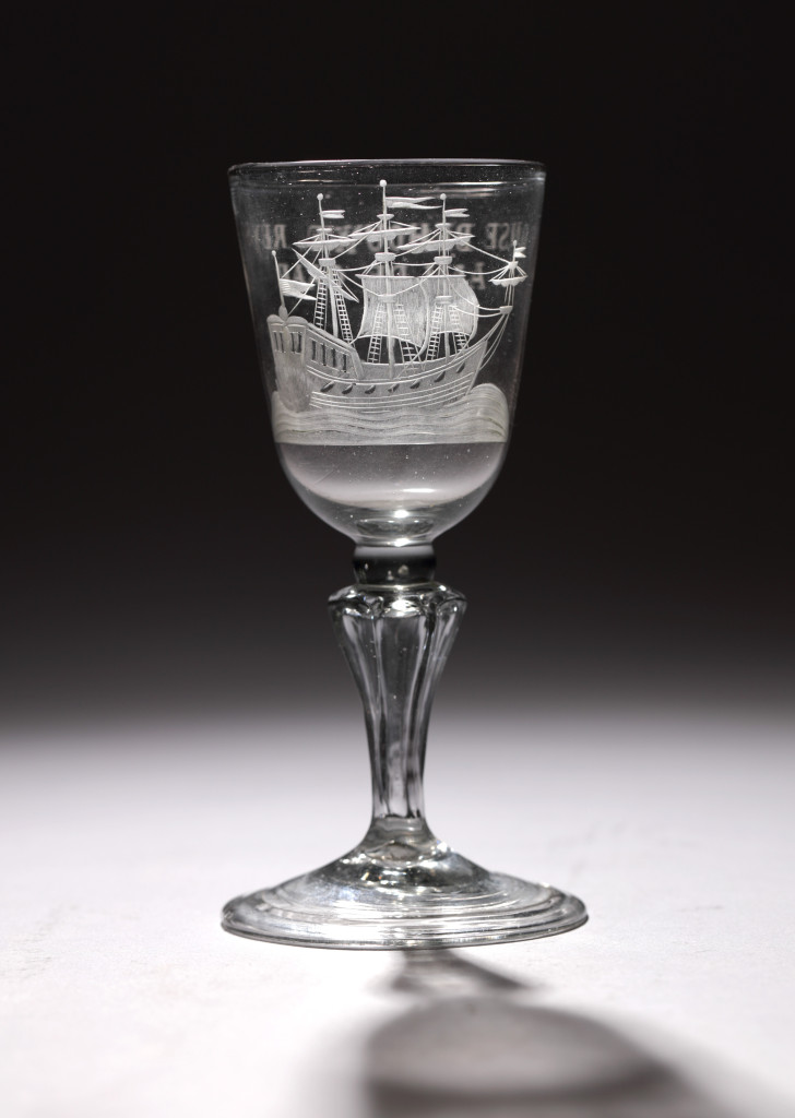 A glass with the engraving of an East-Indiaman and with text "HET WEL VAAREN VAN DE OOSTINDISCHE COMPAGNIE"