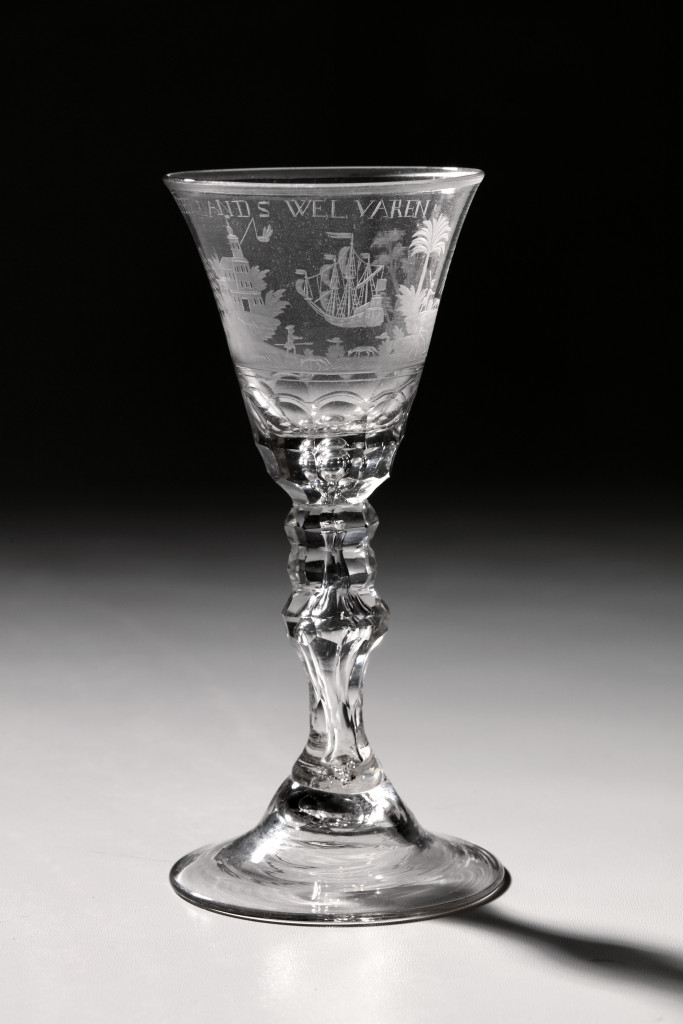 A glass with the engraving of a countryside with farmers, herdsmen and and East-Indiaman in the background, with text "HET LANDS WELVAREN"